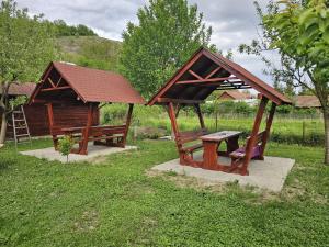 a small wooden pavilion with a bench and a house at Casute la "Doi pasi de Castel" in Hunedoara