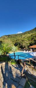 a swimming pool with palm trees next to a mountain at Pousada do Coura in Pouso Alto