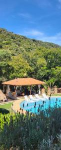 a swimming pool with a gazebo next to a mountain at Pousada do Coura in Pouso Alto