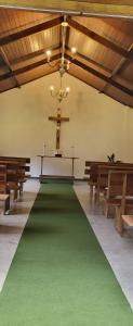 a church with a cross on the wall and a green carpet at Pousada do Coura in Pouso Alto