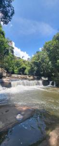 a river with a waterfall and trees in the background at Pousada do Coura in Pouso Alto