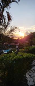 a sunset over a garden with a stone path at Pousada do Coura in Pouso Alto