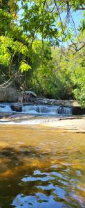 a river with a bridge and a waterfall at Pousada do Coura in Pouso Alto