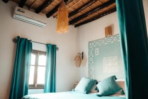 a bedroom with a bed with blue curtains and a window at Dar Haroun in Rissani
