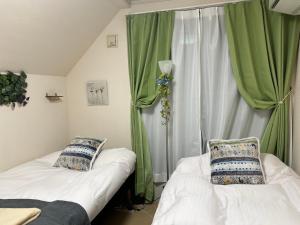 2 camas en una habitación con cortinas verdes en Naotoko Minpaku #HG1, en Tokio