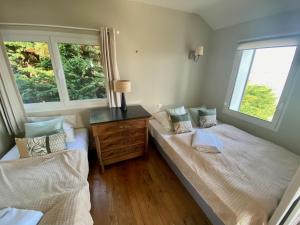 a bedroom with two beds and a dresser and two windows at Cottage Pêcheur + Annexe 12pers vue Mont St-Michel in Champeaux