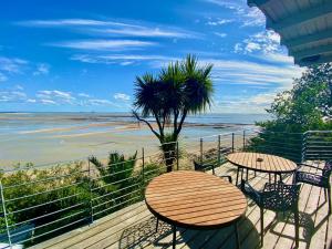 a balcony with tables and chairs and a view of the beach at Cottage Pêcheur + Annexe 12pers vue Mont St-Michel in Champeaux