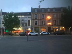 uma rua da cidade com carros estacionados em frente aos edifícios em Hotel Bar Restaurant Couleurs Sud em Charleville-Mézières
