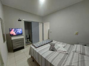 a bedroom with a bed and a flat screen tv at Acomodações no Jardim Tropical em Rondonópolis in Rondonópolis