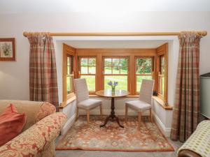 a living room with a table and chairs and windows at Plum Tree Cottage in Castleton