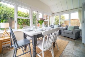 a dining room with a table and chairs and windows at Brambles in Brancaster