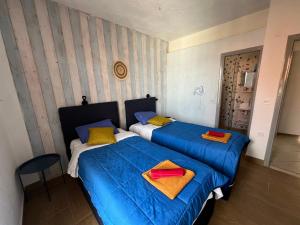 2 camas en una habitación con sábanas azules y almohadas amarillas en Avra Boutique en Benitses