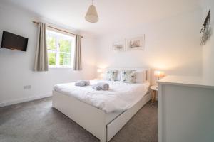 a bedroom with a white bed with a window at Brambles in Brancaster