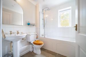 a bathroom with a toilet and a sink and a tub at Brambles in Brancaster +27 photos