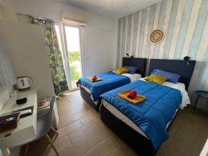 a bedroom with two beds with blue sheets and a window at Avra Boutique in Benitses