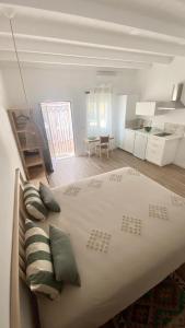 a white bedroom with a large bed with pillows at Quinta Almargem Lusitano - Farm House in Tavira