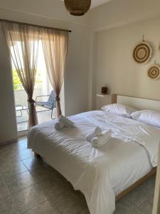 a bedroom with a white bed with towels on it at Sun & Sea in Nea Iraklia