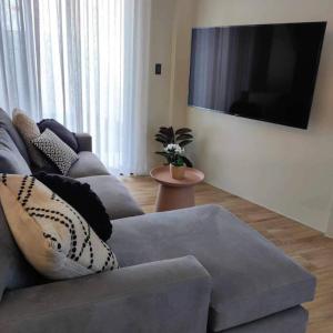 a living room with a couch and a flat screen tv at Cozy Pool Villa near SM Pampanga and Sky Ranch Pampanga in San Fernando