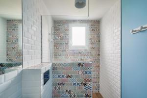 a bathroom with mosaic tiles on the wall at À 200m de la plage de Langoz - Maison pour 10 in Loctudy