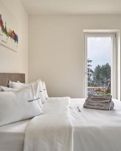 a white bed with white sheets and a window at SalvatoreHomes - Luxury Villa with private Garden & BBQ in San Zeno di Montagna