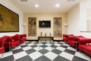 a waiting room with red chairs and a flat screen tv at Hotel Catalunya in Alghero