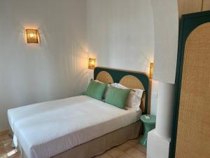 a bedroom with a bed with green and white pillows at Maison d'Orange - La Pinede in Saint-Tropez