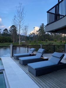 une terrasse avec des canapés et des chaises à côté d'une masse d'eau dans l'établissement Monarch Campestre, à Rionegro