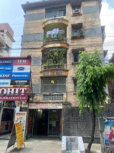 un edificio de ladrillo alto con un árbol delante de él en Ps Homes in central Kolkata en Calcuta