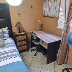 Un escritorio en un dormitorio con una cama y un escritorio. en Rooms @Kosmos, en Mokopane