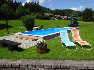 2 chaises et une piscine sur gazon dans l'établissement Haus Oberfeichtner, à Mitterbach am Erlaufsee