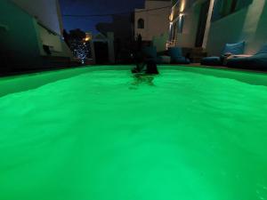 a person in a swimming pool with green illumination at Mata's Apartments in Tinos