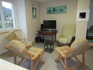 ein Wohnzimmer mit 3 Stühlen und einem TV in der Unterkunft La Grange in Vals-les-Bains