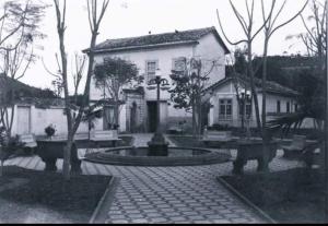 a black and white photo of a house with a fountain at Casa Centenária localizada no coração da cidade in São Luiz do Paraitinga