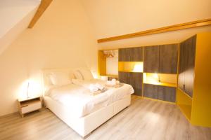 a bedroom with a white bed and a wooden floor at Appartement Le Ch'ti Alsacien in Eguisheim