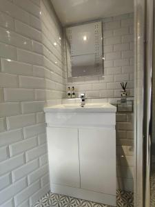 Baño blanco con lavabo y espejo en Queen's Apartment in Cardigan, Cardigan Bay en Cardigan
