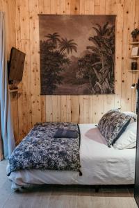 Schlafzimmer mit einem Bett mit Wandgemälde in der Unterkunft myinsolite - Cocon Tropical, jacuzzi, énigme in Vauvert