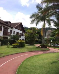 a house with a palm tree and a road at Lagos de Itaipava in Bom Sucesso
