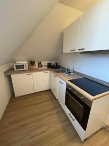 une petite cuisine avec des armoires blanches et un évier dans l'établissement BullsLiving Seeapartment 4 AM CORSO, à Velden am Wörther See