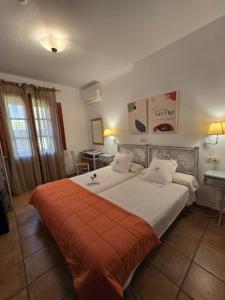 - une chambre avec un grand lit et une couverture orange dans l'établissement Hotel Rural La Casa De Pasarón, à Pasarón