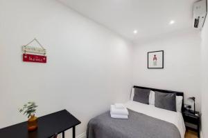 a white bedroom with a bed and a table at Indipendent flat with patio in Greenford