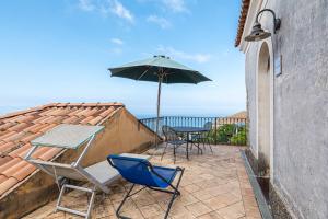 a patio with a table and chairs and an umbrella at Sparviero - ACrapa Mangia in Santa Maria di Castellabate