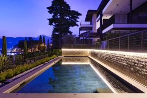 a swimming pool with lights on the side of a building at SalvatoreHomes - Luxurious Dreamview Waterfront Apartment in Torri del Benaco with Pool - Casa Azura - a 5 Star Luxury Collection at Lake Garda in Torri del Benaco