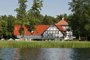 una casa grande junto a un cuerpo de agua en Jabłoń Lake Resort, en Pisz