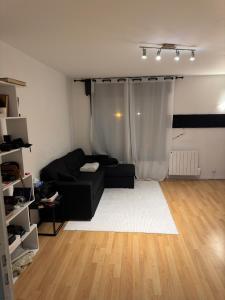 a living room with a black couch and a white rug at Grand appartement lumineux in Noisy-le-Grand