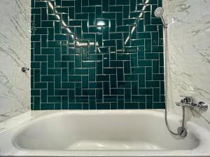 uma banheira na casa de banho com uma parede de azulejos verdes em Новобудова в Центрі біля набережної em Kremenchuk