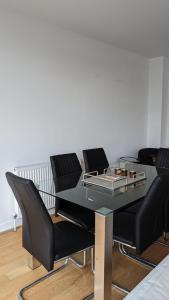 einen Esstisch mit schwarzen Stühlen und einer Glasplatte in der Unterkunft Cozy 2 Bedrooms by Shoreditch in London
