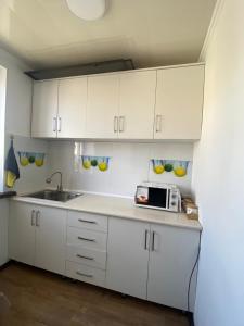 uma cozinha com armários brancos e um micro-ondas em 31 em Naryn