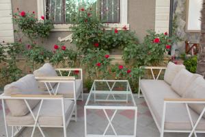 a patio with two chairs and tables and red roses at Museum Guest House-Muzey Ailəvi Qonaq Evi in Sheki