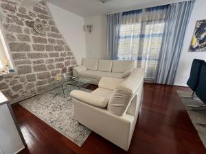 una sala de estar con 2 sofás blancos y una pared de piedra. en Apartments Villa De Blue, en Bol