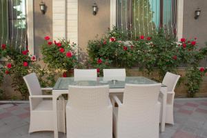 une table avec des chaises blanches et des roses rouges dans l'établissement Museum Guest House-Muzey Ailəvi Qonaq Evi, à Shaki
